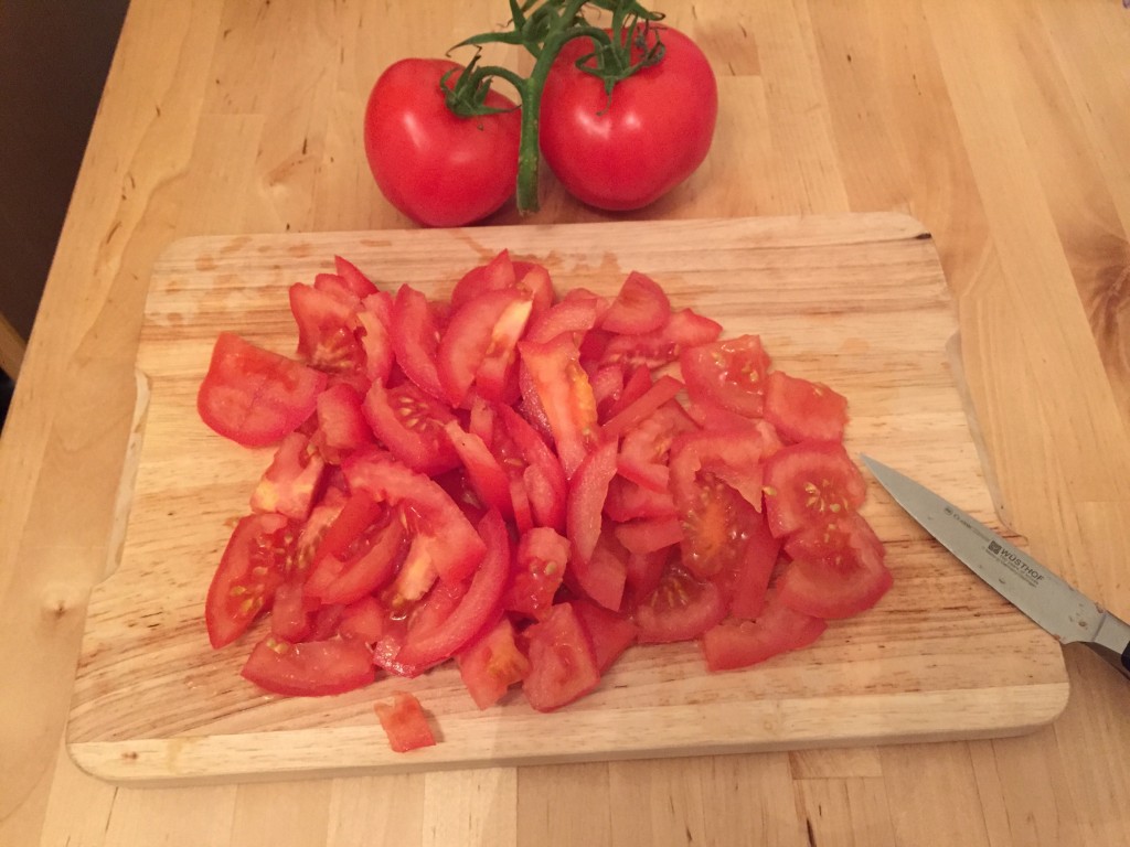 Geschnittene Tomaten auf einem Holzschneidebrett. Außerdem das Messer, mit dem ich das Tomaten-Massaker angerichtet habe. 